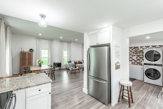375 Mount Vernon Rd, Bethpage, TN 37022 - kitchen featuring freestanding refrigerator, stacked washer and dryer, white cabinetry, light wood finished floors, and light stone countertops