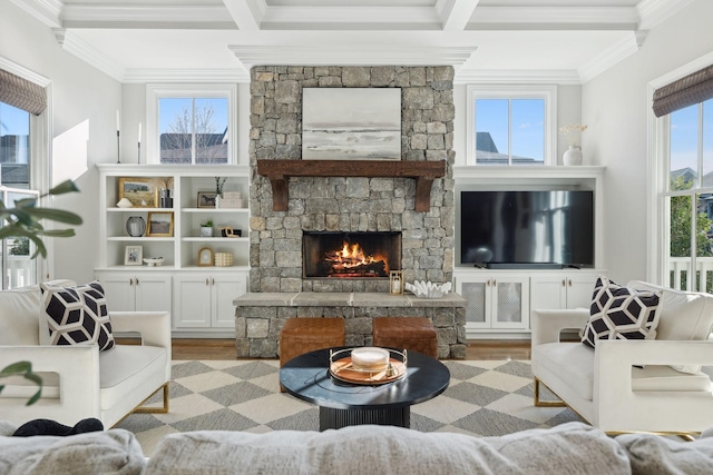 living room with crown molding, beamed ceiling, light wood-style flooring, and a stone fireplace