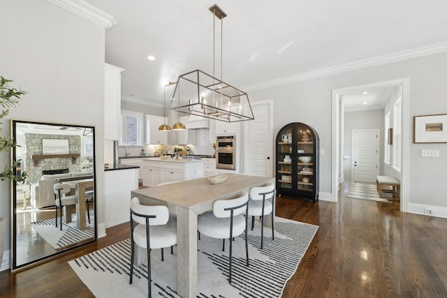 dining room featuring a chandelier, dark wood-style flooring, baseboards, and crown molding