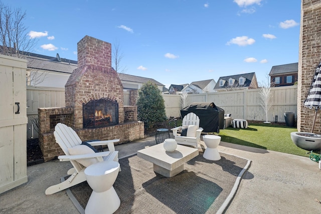 view of patio / terrace featuring a fenced backyard, area for grilling, and an outdoor brick fireplace