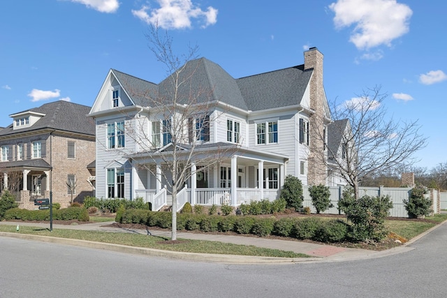 view of front facade with fence, a porch, and a chimney
