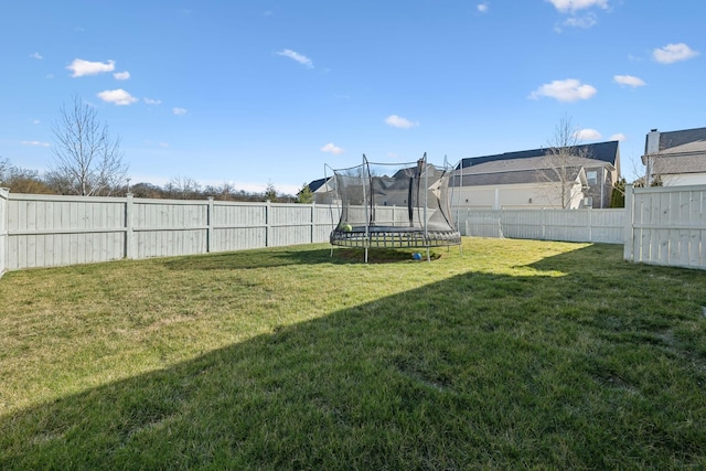 view of yard with a trampoline and a fenced backyard