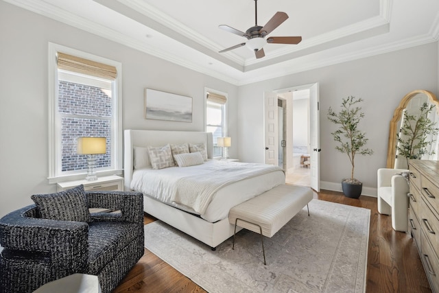 bedroom with a tray ceiling, crown molding, baseboards, and dark wood finished floors