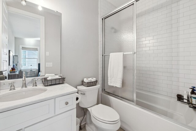 full bathroom featuring combined bath / shower with glass door, toilet, and vanity