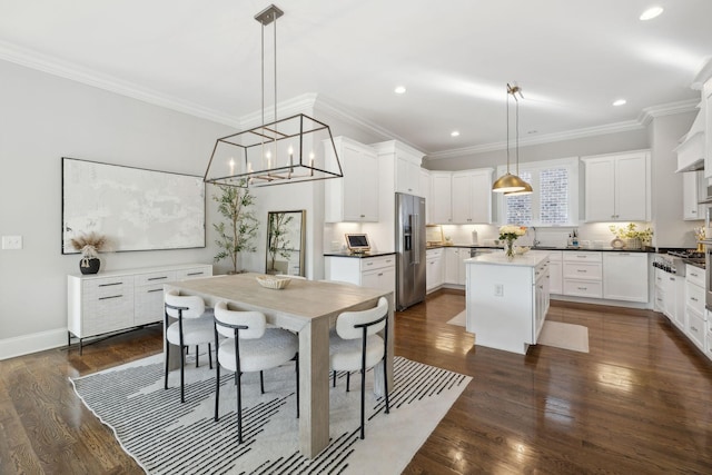 kitchen with dark wood-type flooring, high end fridge, white cabinetry, and crown molding
