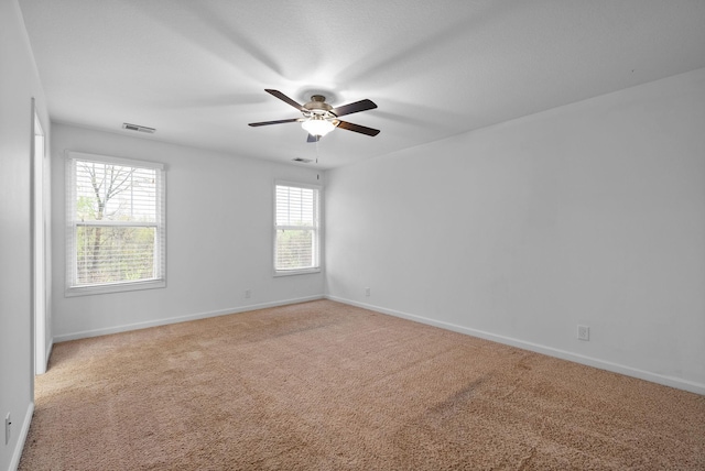 carpeted empty room with visible vents, ceiling fan, and baseboards