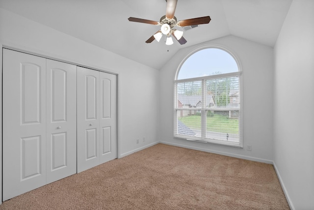 unfurnished bedroom featuring a closet, baseboards, ceiling fan, carpet, and lofted ceiling