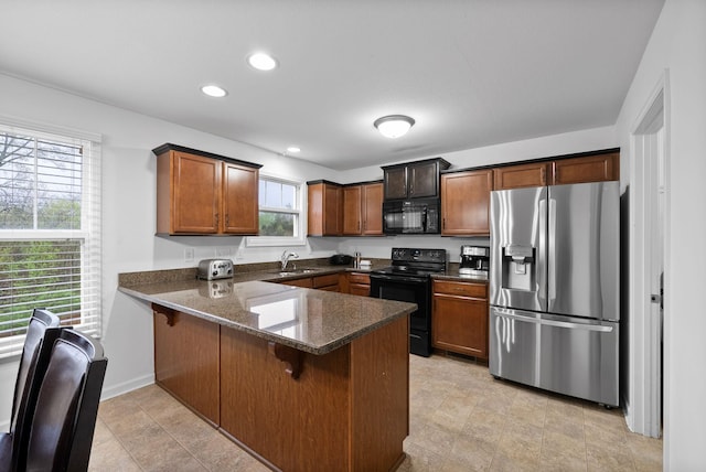 kitchen with a peninsula, black appliances, recessed lighting, a breakfast bar, and a sink