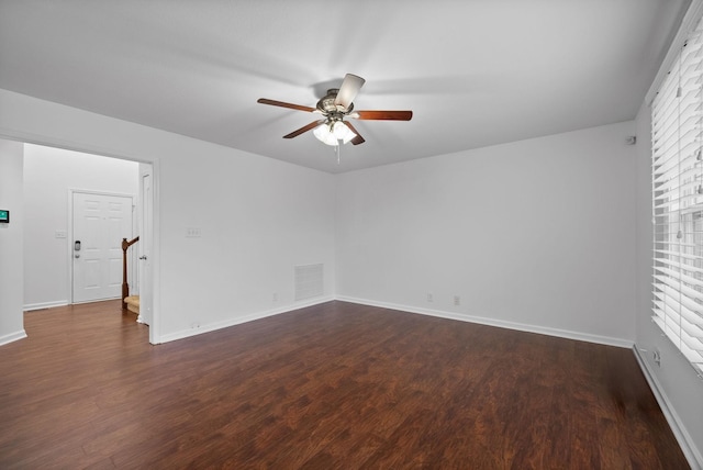 empty room featuring baseboards, stairway, dark wood-style floors, visible vents, and ceiling fan