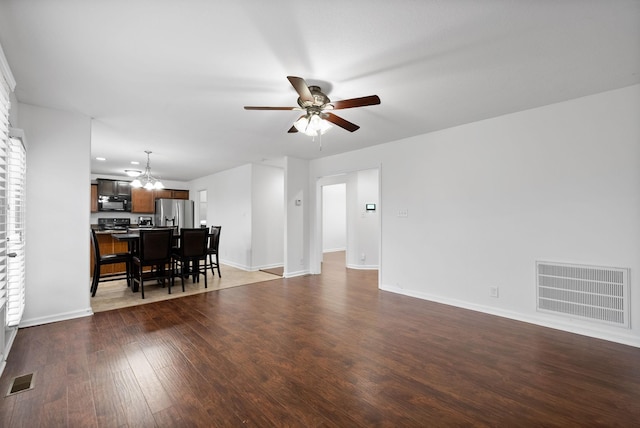 living room with visible vents, dark wood-style flooring, baseboards, and ceiling fan with notable chandelier