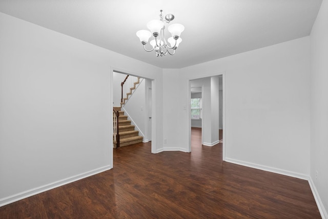 spare room with stairs, baseboards, an inviting chandelier, and wood finished floors