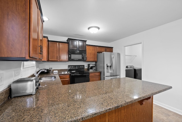 kitchen with separate washer and dryer, dark stone countertops, a peninsula, black appliances, and a sink