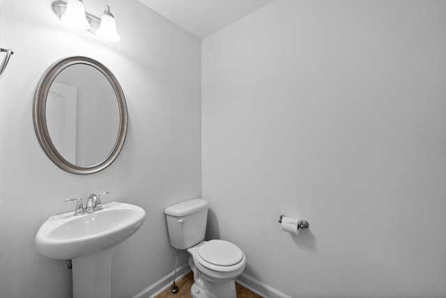 bathroom featuring toilet, a sink, and baseboards