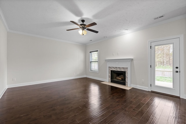 unfurnished living room featuring visible vents, a tiled fireplace, ornamental molding, a ceiling fan, and dark wood-style floors