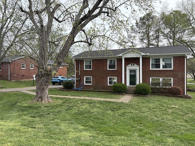 raised ranch featuring brick siding, entry steps, and a front lawn