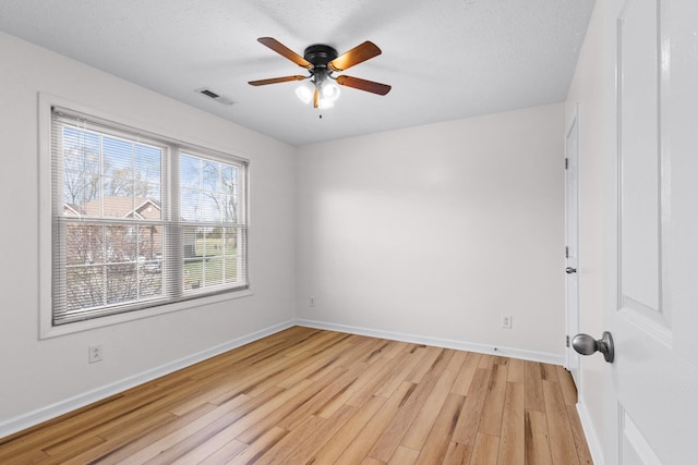 unfurnished room with light wood-type flooring, baseboards, a textured ceiling, visible vents, and ceiling fan