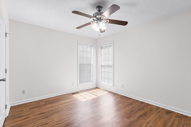 empty room featuring visible vents, baseboards, a ceiling fan, and wood finished floors
