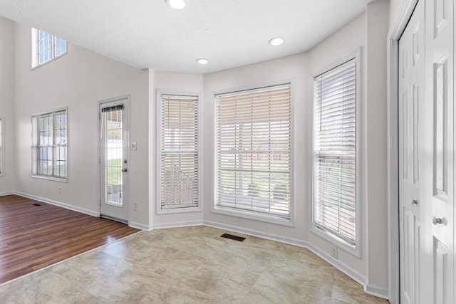 foyer entrance with wood finished floors, baseboards, visible vents, and recessed lighting