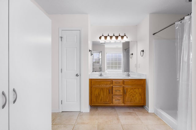 bathroom with tile patterned flooring, a shower with shower curtain, a sink, double vanity, and baseboards