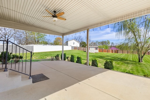 view of patio / terrace with a storage shed, a fenced backyard, a ceiling fan, and an outdoor structure