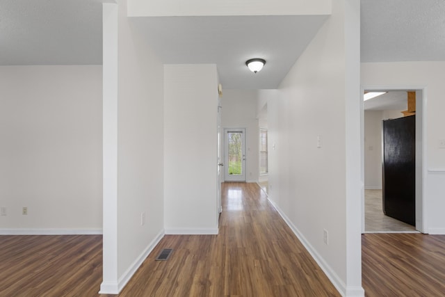 hall with wood finished floors, baseboards, and visible vents