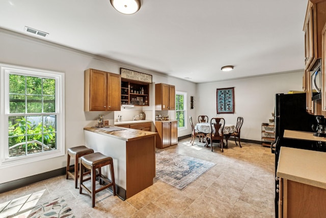 1132 Roseland Dr, Columbia, TN 38401 - kitchen featuring a breakfast bar, brown cabinetry, plenty of natural light, and visible vents