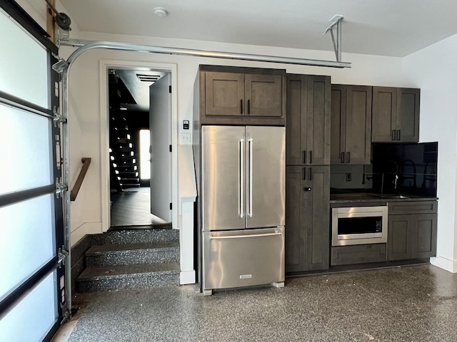 kitchen featuring dark countertops, dark brown cabinetry, appliances with stainless steel finishes, and plenty of natural light
