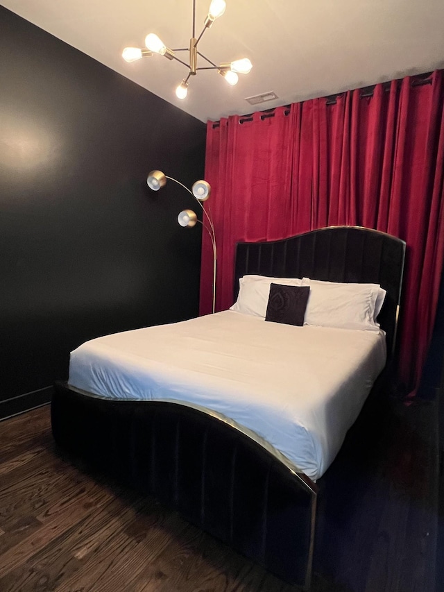 bedroom with wood finished floors, visible vents, and an inviting chandelier