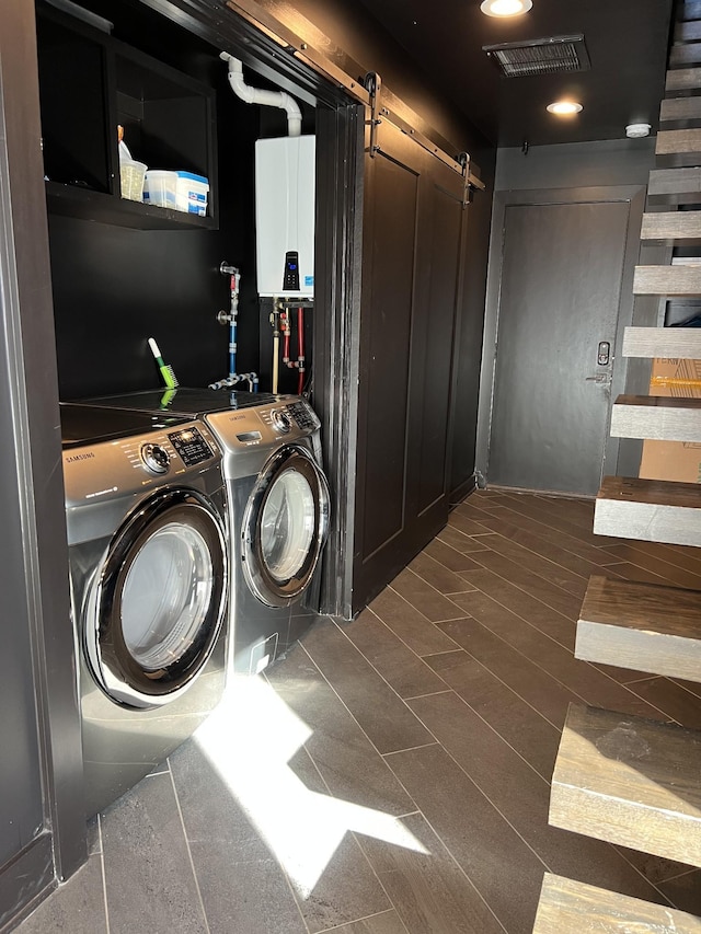 laundry room featuring tankless water heater, a barn door, visible vents, independent washer and dryer, and laundry area