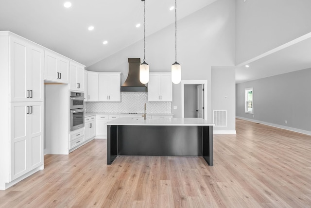 307 Riverview Dr, Dover, TN 37058 - kitchen with custom range hood, stainless steel double oven, high vaulted ceiling, a center island with sink, and light countertops