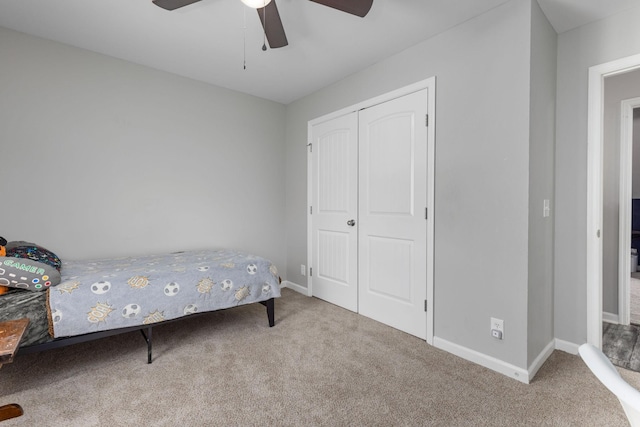carpeted bedroom with a closet, baseboards, and a ceiling fan