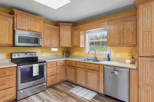 kitchen featuring light countertops, light wood-type flooring, a sink, and stainless steel appliances