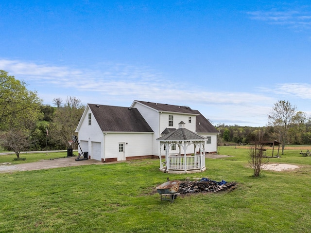 exterior space with aphalt driveway, a gazebo, a fire pit, and a lawn
