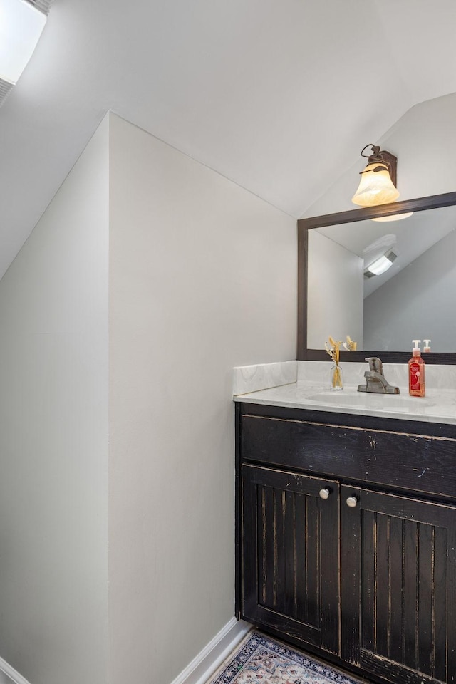 bathroom featuring vanity, baseboards, and vaulted ceiling