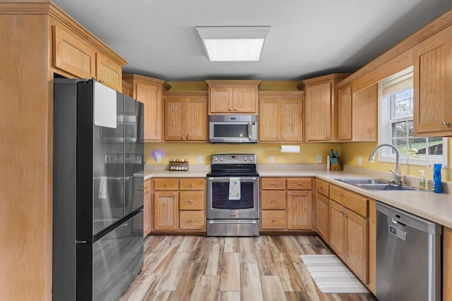kitchen with a sink, light countertops, light wood finished floors, and stainless steel appliances