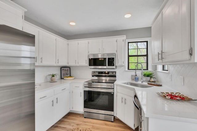 kitchen with light countertops, a sink, white cabinetry, and appliances with stainless steel finishes