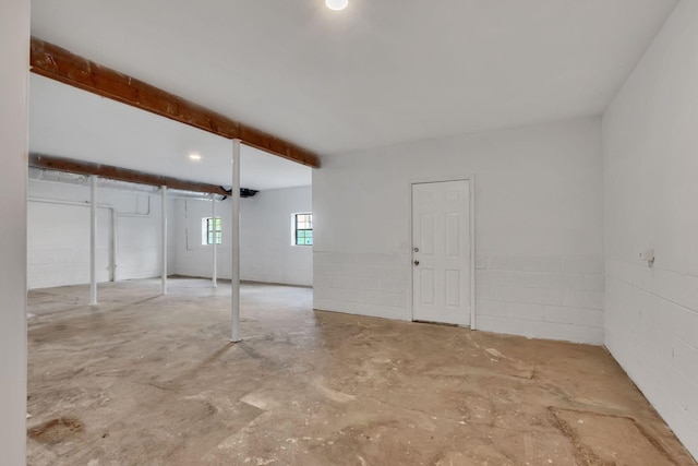interior space with unfinished concrete flooring and concrete block wall