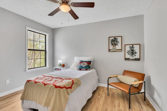bedroom featuring light wood finished floors, baseboards, and a ceiling fan