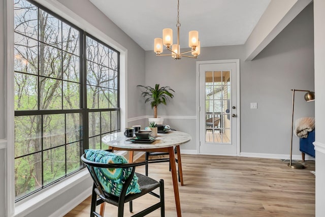 dining area with baseboards, light wood finished floors, and a notable chandelier