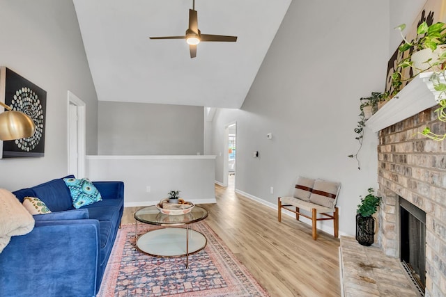 living area featuring baseboards, a ceiling fan, a fireplace, wood finished floors, and high vaulted ceiling