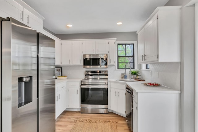kitchen featuring a sink, light countertops, light wood finished floors, recessed lighting, and stainless steel appliances