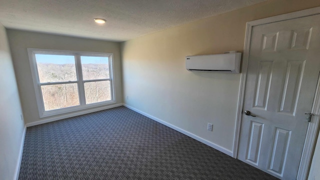 empty room featuring baseboards, an AC wall unit, dark carpet, and a textured ceiling