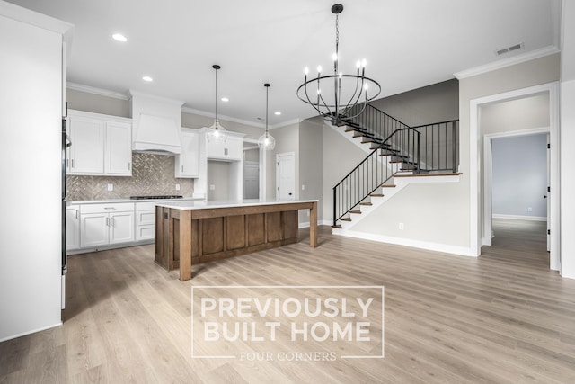 kitchen featuring white cabinets, custom exhaust hood, cooktop, and visible vents
