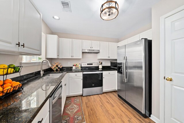 kitchen with visible vents, a sink, under cabinet range hood, light wood finished floors, and stainless steel appliances