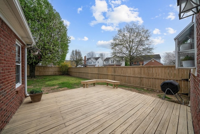 wooden terrace with a fenced backyard and a lawn