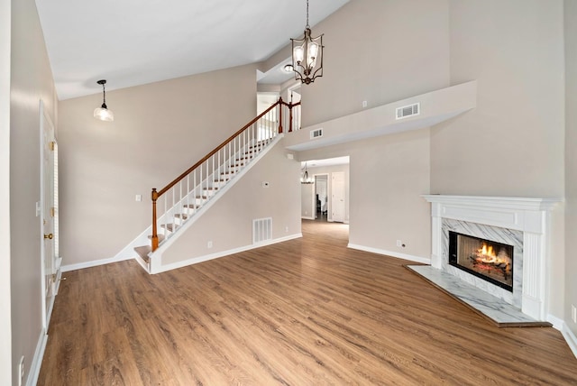 unfurnished living room featuring stairs, visible vents, and wood finished floors