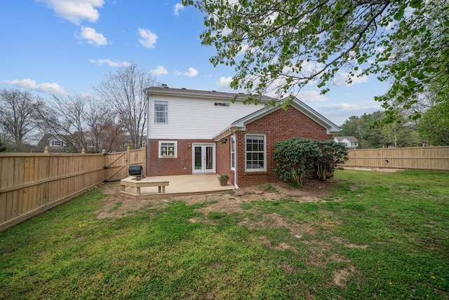 rear view of property featuring a yard, brick siding, french doors, and a fenced backyard