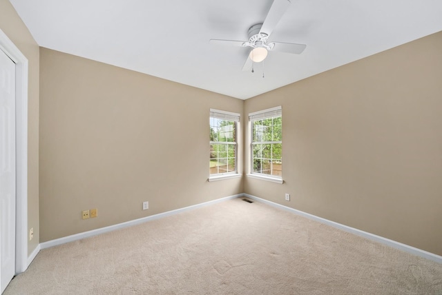 empty room featuring visible vents, carpet flooring, baseboards, and a ceiling fan