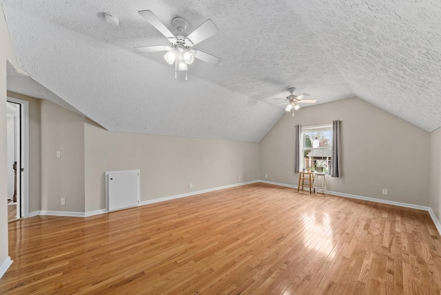 additional living space with a textured ceiling, light wood finished floors, baseboards, and a ceiling fan