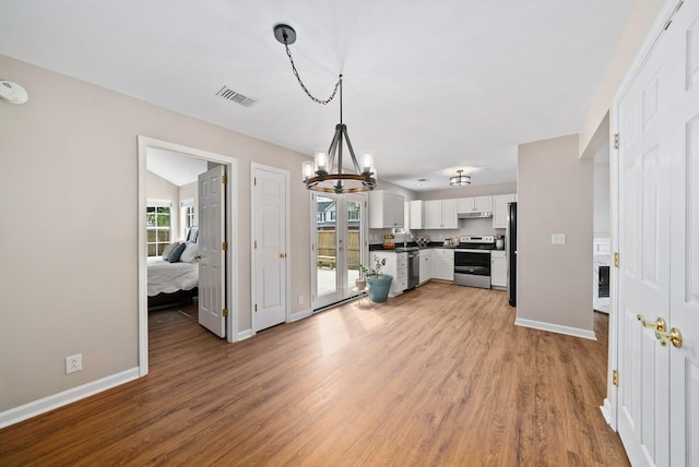 kitchen featuring stainless steel appliances, light wood finished floors, a notable chandelier, and dark countertops